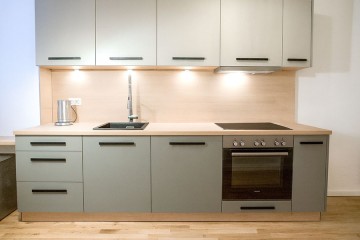 Affordable mid-range kitchen up to €2000 – beige fronts, wood top, black handles. - Polmobel Küchen Berlin