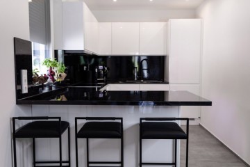 Polmöbel Berlin modern beyaz mutfak, siyah parlak tezgâh ile. - Polmobel Küchen Berlin